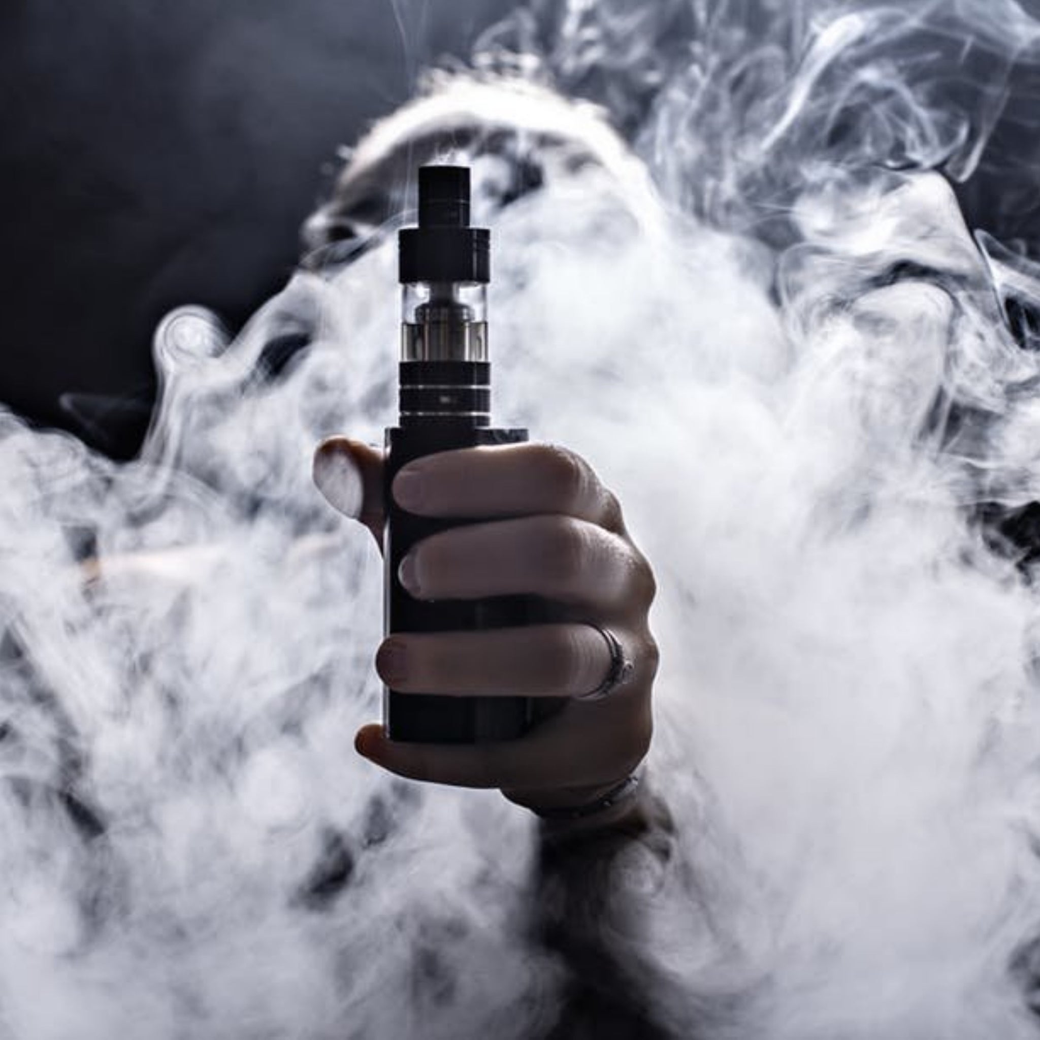 Hand holding vape with smoke around everything